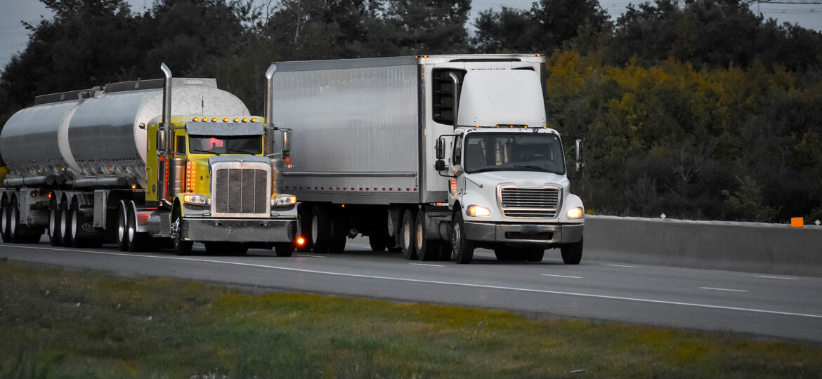 trailer-trucks-driving-on-the-road-surrounded-by-beautiful-green-trees